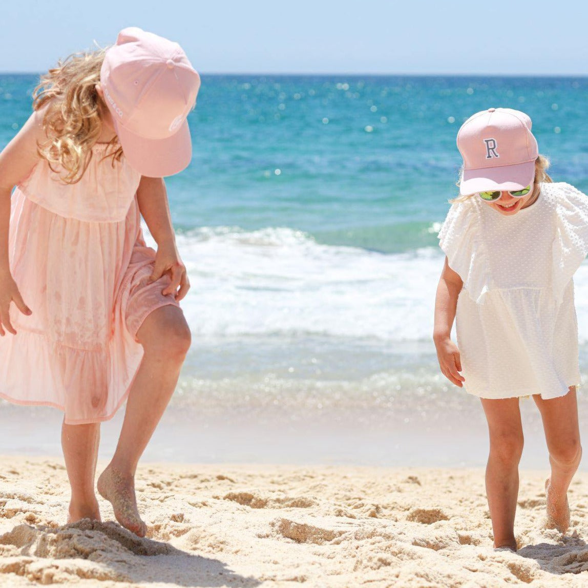 Kids wearing matching personalised pink baseball caps with their initials. Cubs & Co. Australia.