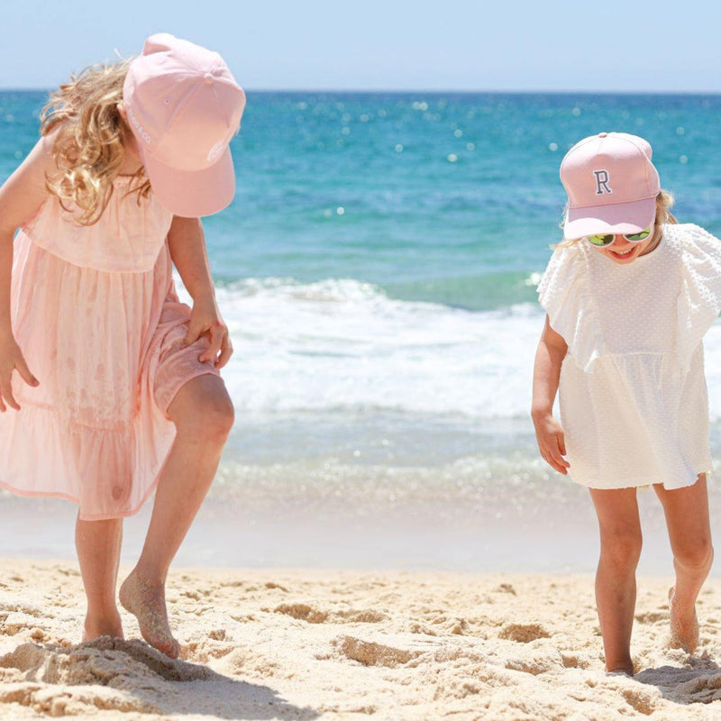Kids wearing matching personalised pink baseball caps with their initials. Cubs & Co. Australia.
